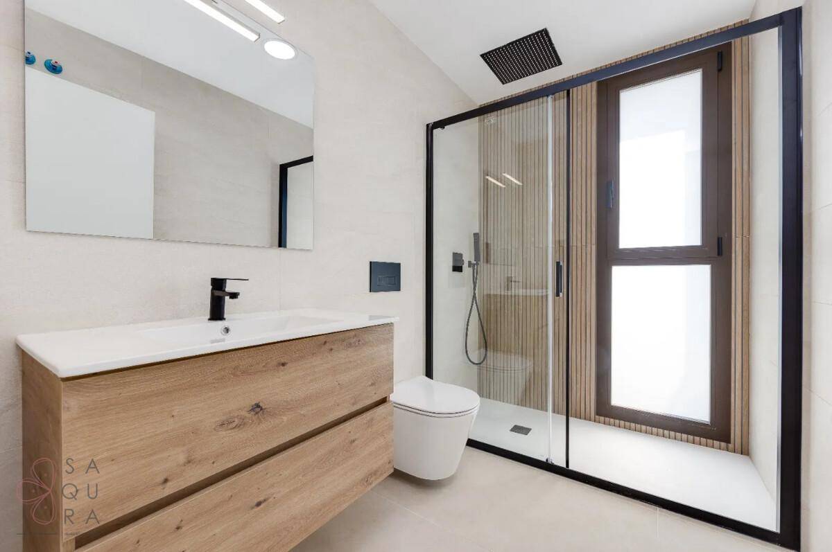 Helles Badezimmer mit großer Duschkabine, Holzwaschtisch und Fenster für Tageslicht.
