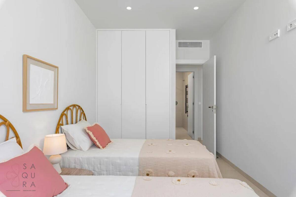 Kinder- oder Gästezimmer mit zwei Einzelbetten und integriertem weißen Kleiderschrank.