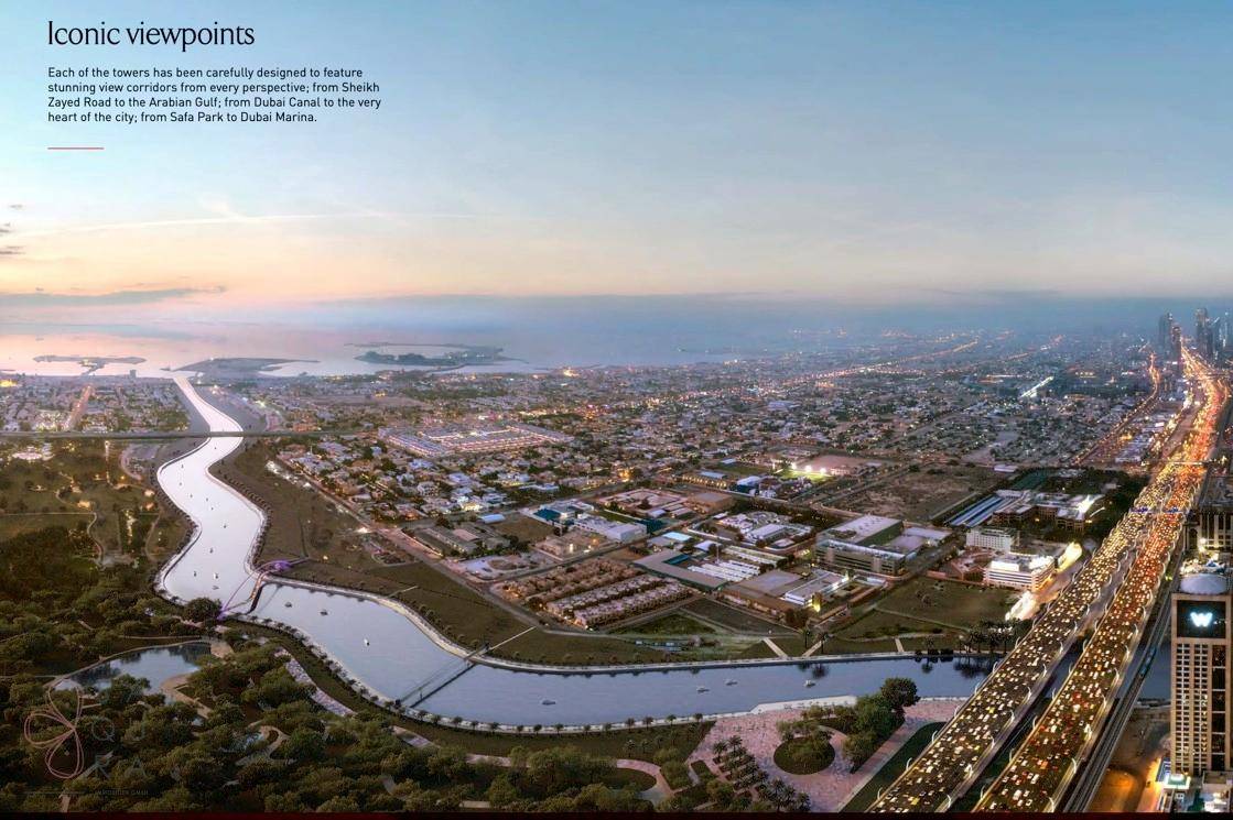 Eine weite Luftaufnahme der Stadt Dubai mit beleuchteten Straßen, Wasserläufen und zahlreichen Gebäuden bei Sonnenuntergang.