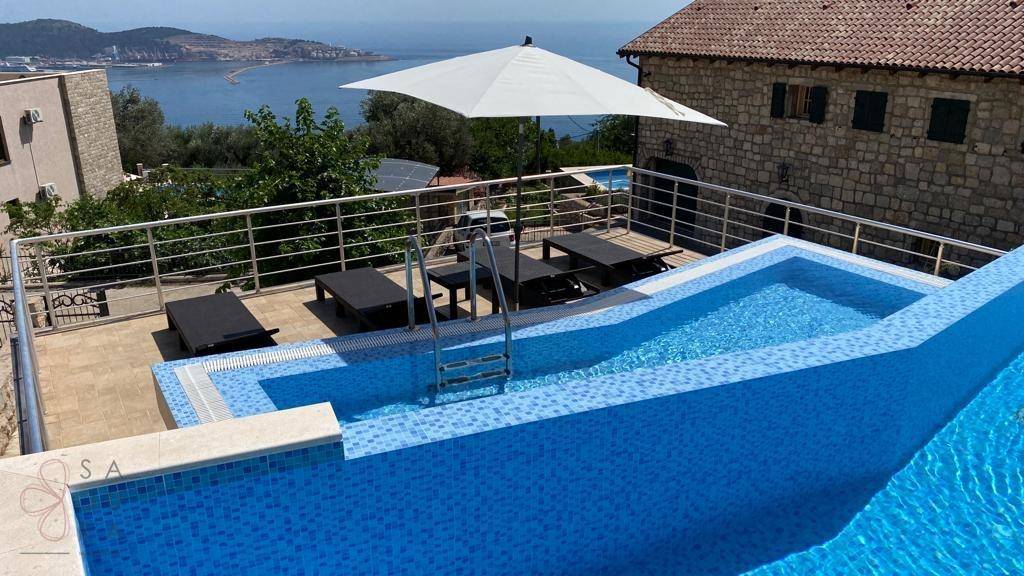 Poolbereich mit Sonnenliegen und weitem Blick auf das Meer und die umliegende Landschaft.