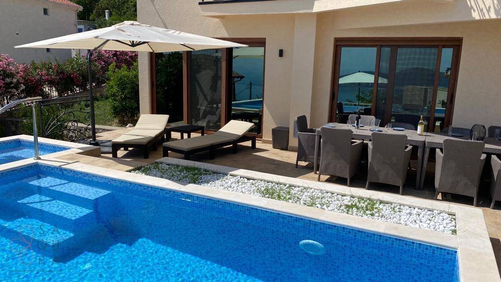 Außenbereich mit Pool, Sonnenliegen und einer möblierten Terrasse neben dem Haus.