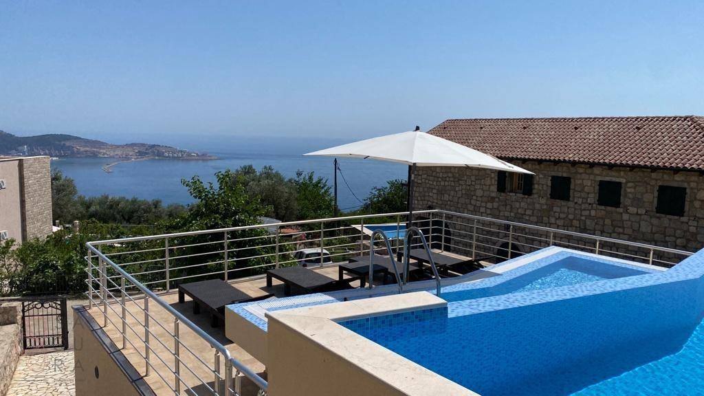 Poolbereich mit Sonnenliegen und weitem Blick auf das Meer und die Küstenlandschaft.