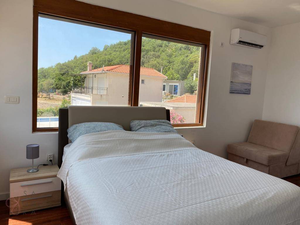 Helles Schlafzimmer mit großem Fenster, Holzboden und Klimaanlage.