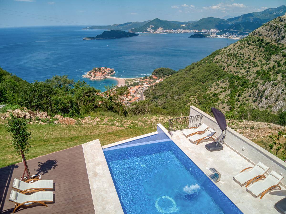 Infinity-Pool mit Holzdeck und spektakulärem Panoramablick auf das Meer und die Küstenlandschaft.
