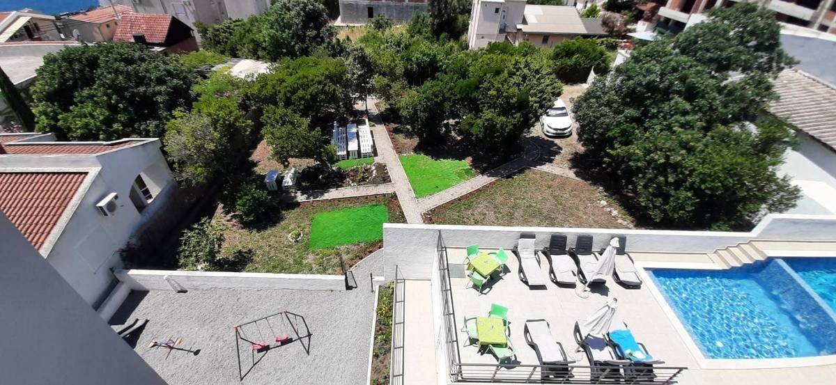 Grüne Gartenanlage mit Spielbereich, Liegewiese und angrenzendem Poolbereich.