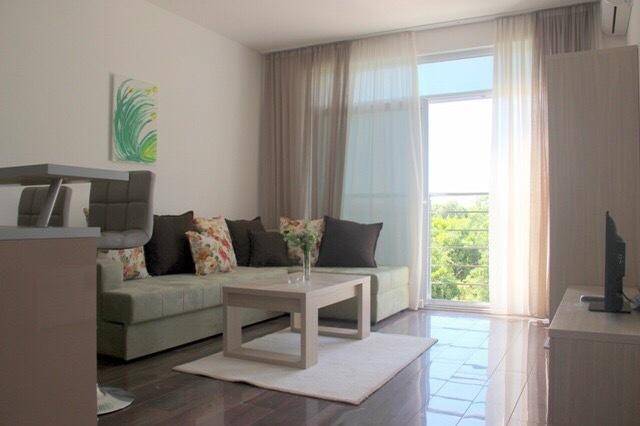 Helles Wohnzimmer mit großem Fenster, Balkonzugang und moderner Einrichtung.