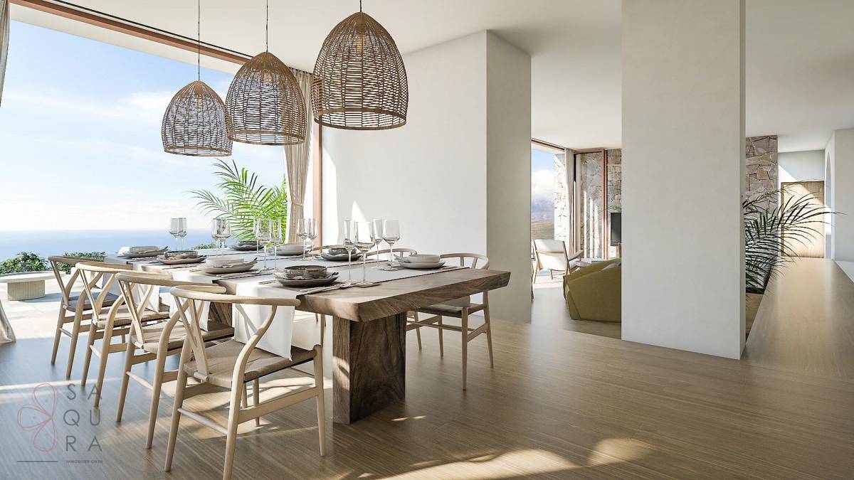Heller Essbereich mit Holztisch, Korblampen und großen Fenstern mit Meerblick.