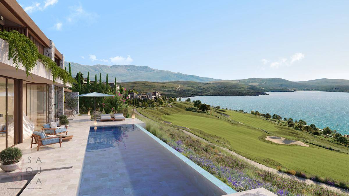 Poolterrasse mit Liegestühlen und weitem Blick über den Golfplatz und das Meer.