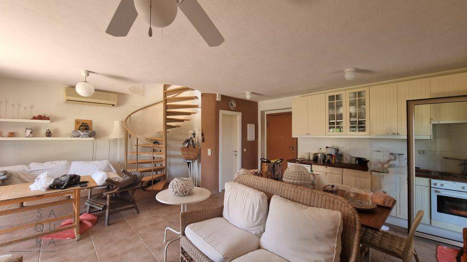 Geräumiger Wohnbereich mit Wendeltreppe, Deckenventilator und integrierter Küchenzeile im Hintergrund.