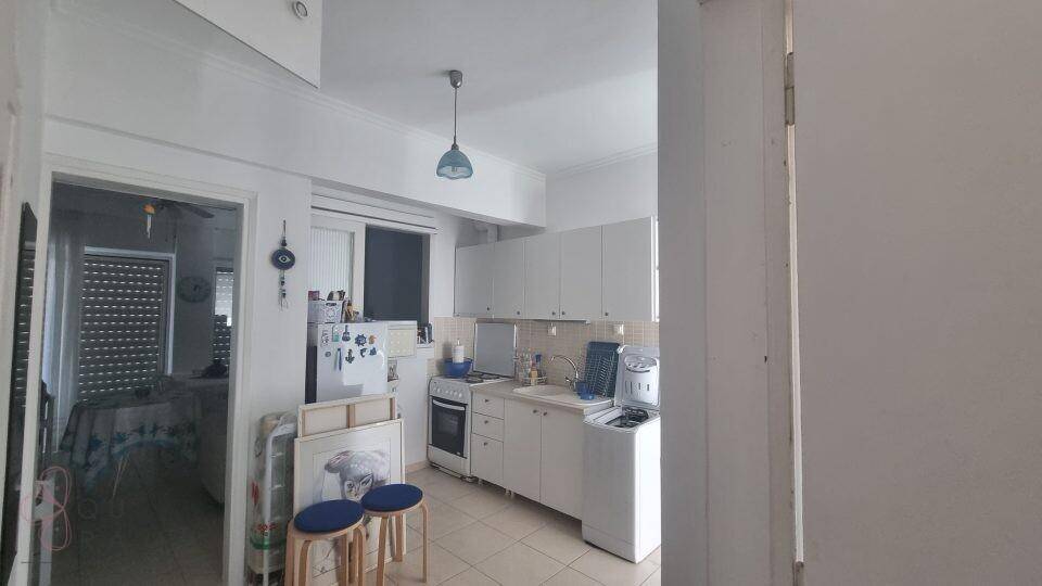 Einfache Küche mit Herd, Kühlschrank und Waschmaschine, ideal für den täglichen Gebrauch.