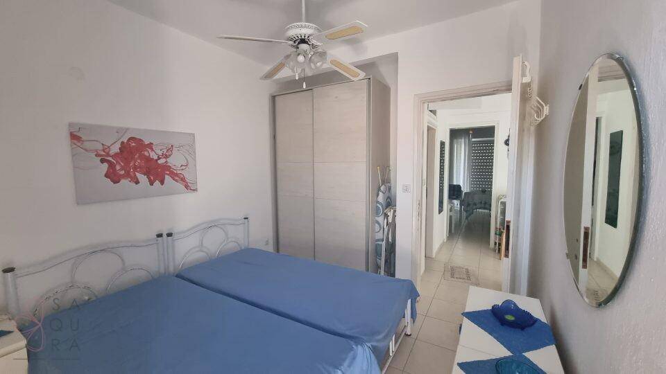 Schlafzimmer mit zwei Einzelbetten, Kleiderschrank und Zugang zu einem weiteren Raum.