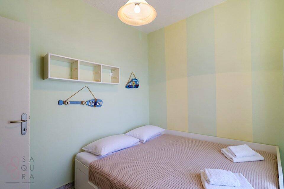 Helles Schlafzimmer mit Einzelbett, maritimer Dekoration und gestreiften Wänden.