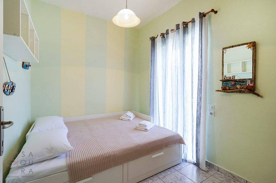 Schlafzimmer mit Einzelbett, gestreiften Wänden und Zugang zu einem kleinen Balkon.