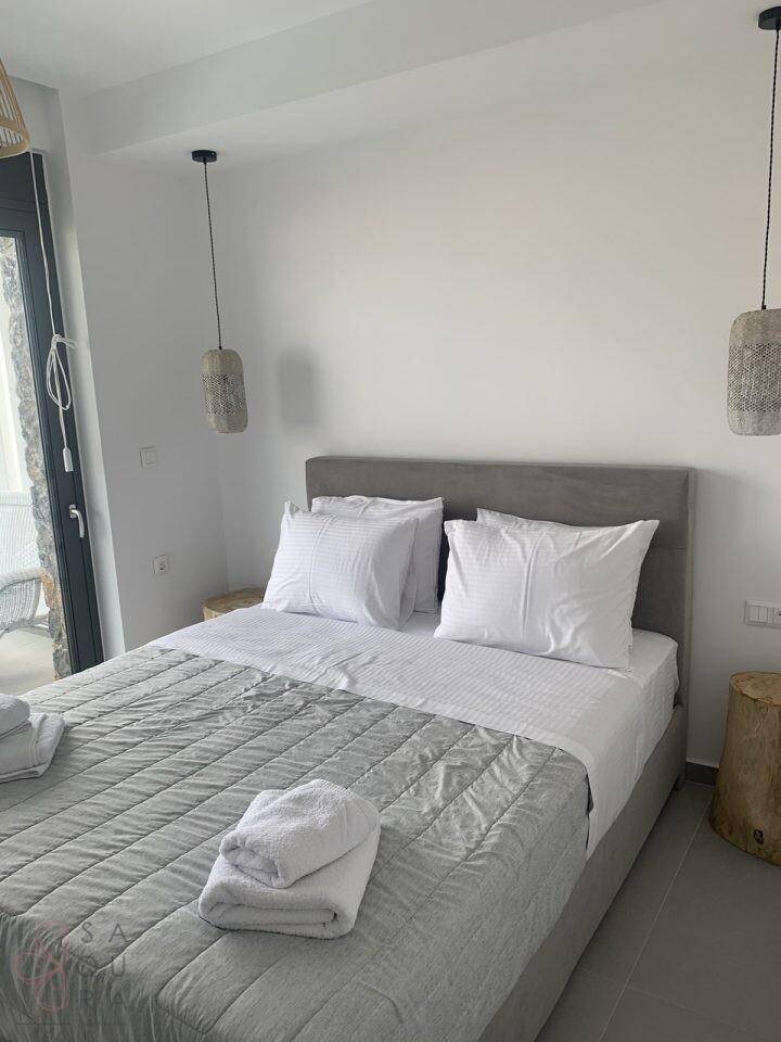 Schlafzimmer mit Doppelbett, modernen Pendelleuchten und Zugang zu einem Außenbereich.