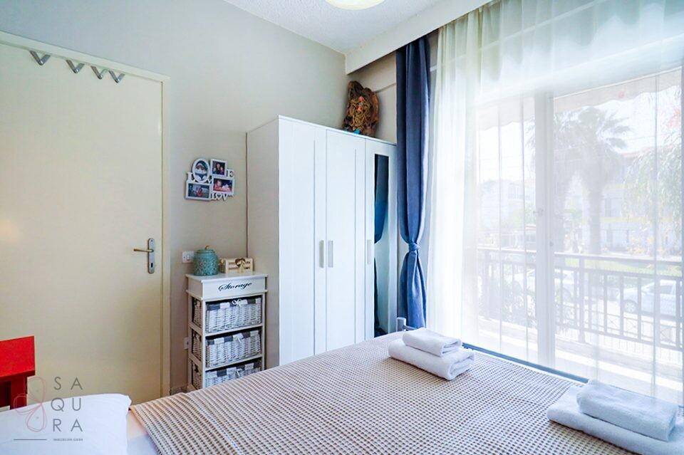 Schlafzimmer mit Doppelbett, weißem Kleiderschrank und großen Fenstern zum Balkon.