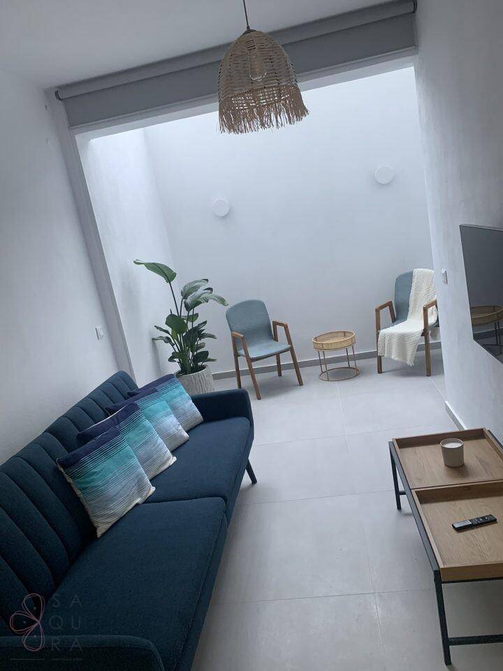 Helles Wohnzimmer mit blauem Sofa, modernen Stühlen und natürlichem Lichteinfall von oben.