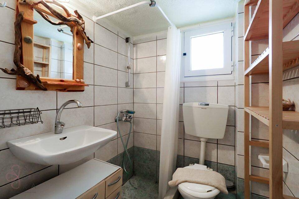 Funktionales Badezimmer mit Dusche, WC, Waschbecken und Fenster für Tageslicht.