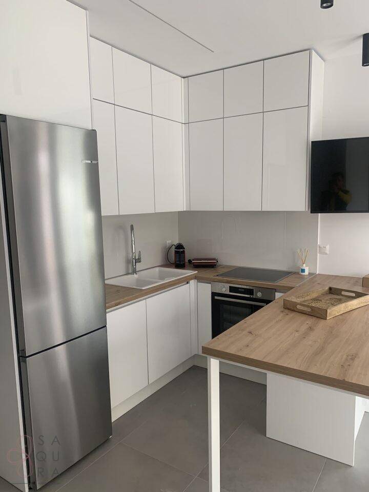 Helle Einbauküche mit weißen Schränken, modernen Geräten und einer Holztheke.