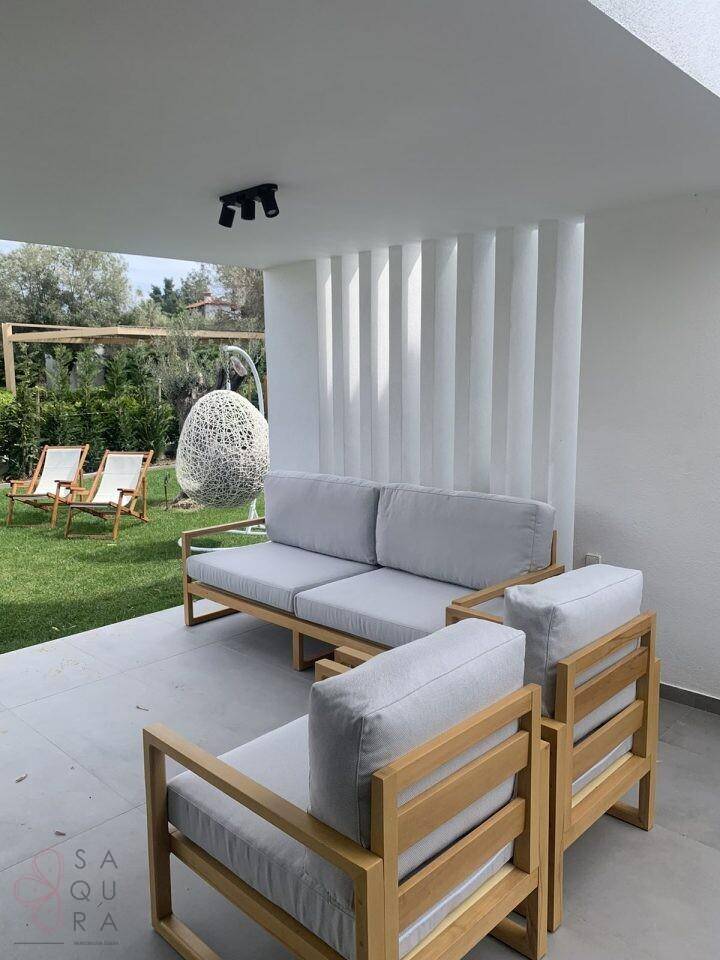 Gemütliche überdachte Lounge-Terrasse mit bequemen Sitzmöbeln und Blick auf den Garten.