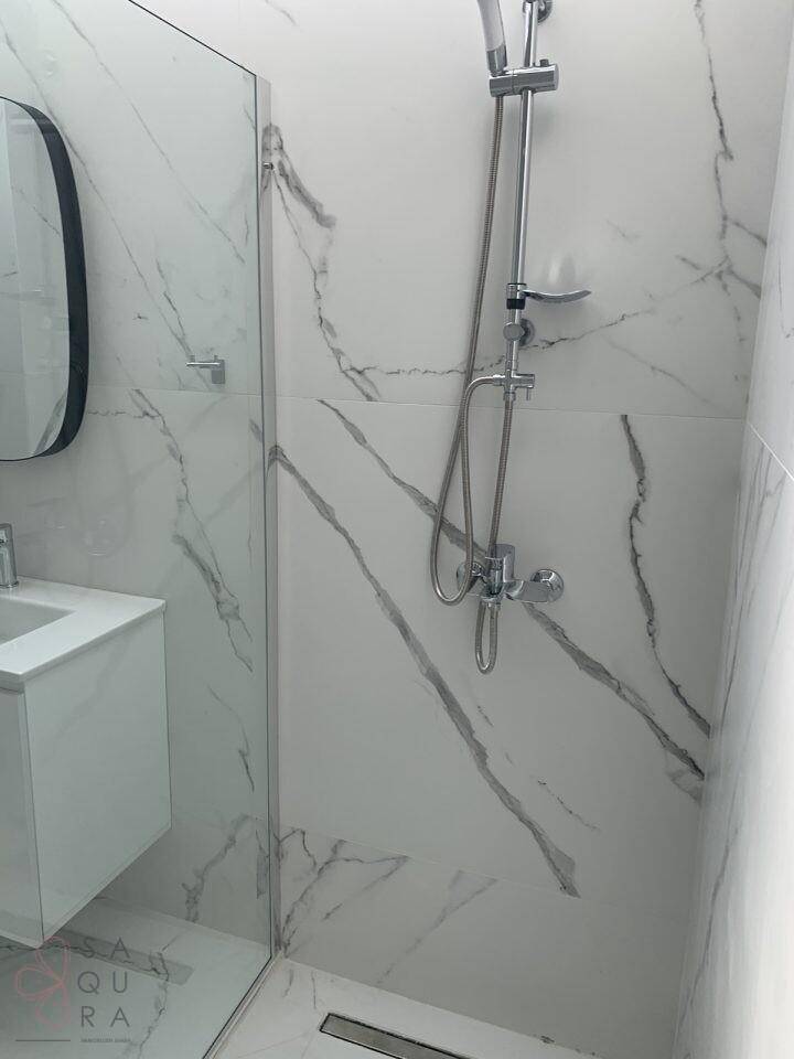 Modernes Badezimmer mit begehbarer Dusche und eleganten Fliesen in Marmoroptik.