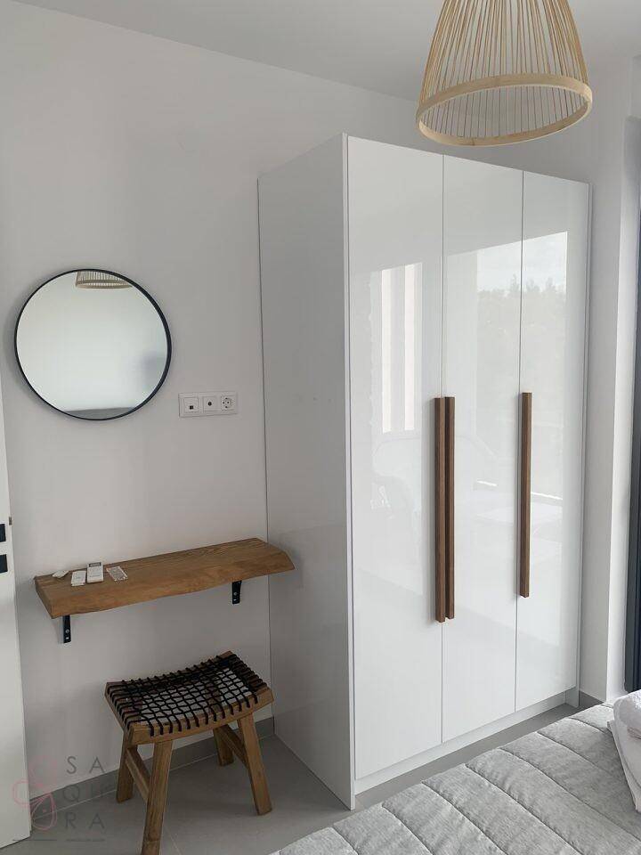 Schlafzimmer mit einem weißen Hochglanzschrank und einem rustikalen Holzregal.