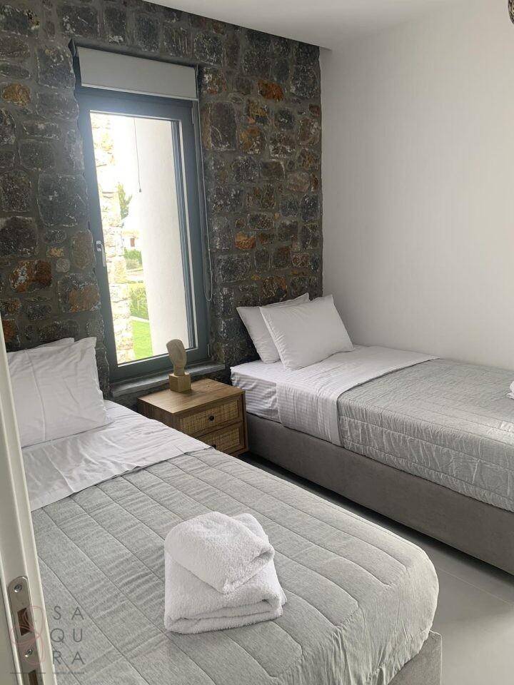 Schlafzimmer mit zwei Einzelbetten, einer dekorativen Steinwand und natürlichem Lichteinfall.