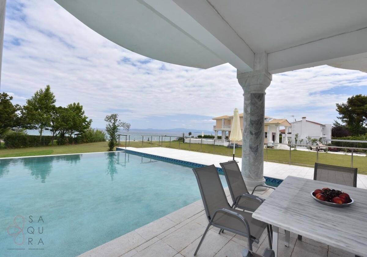 Entspannender Poolbereich mit Sitzgelegenheiten und weitem Blick auf das Meer und die Küste.