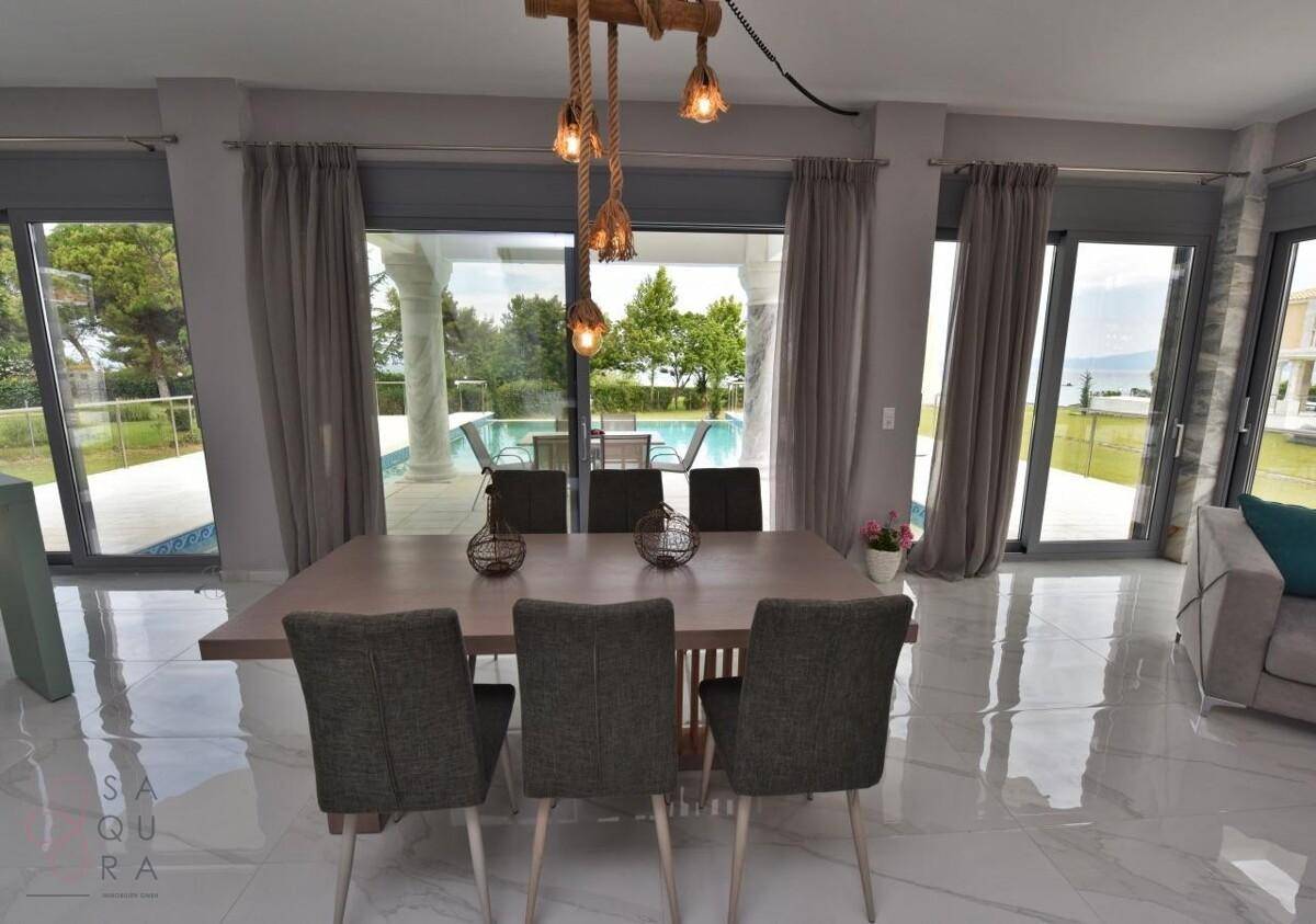 Essbereich mit großem Tisch und direktem Blick auf den Pool und das Meer.