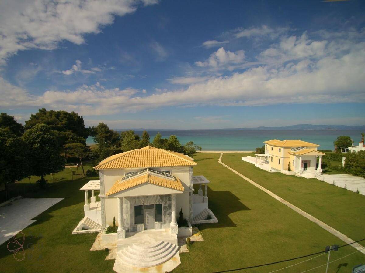 Panoramablick auf die Villa mit weitläufigem Rasen und direktem Zugang zum Meer.