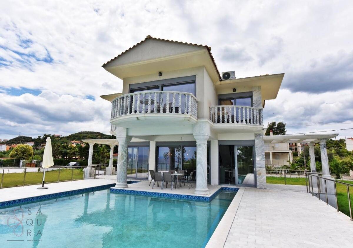 Elegante Villa mit privatem Pool und Balkonen unter einem bewölkten Himmel.