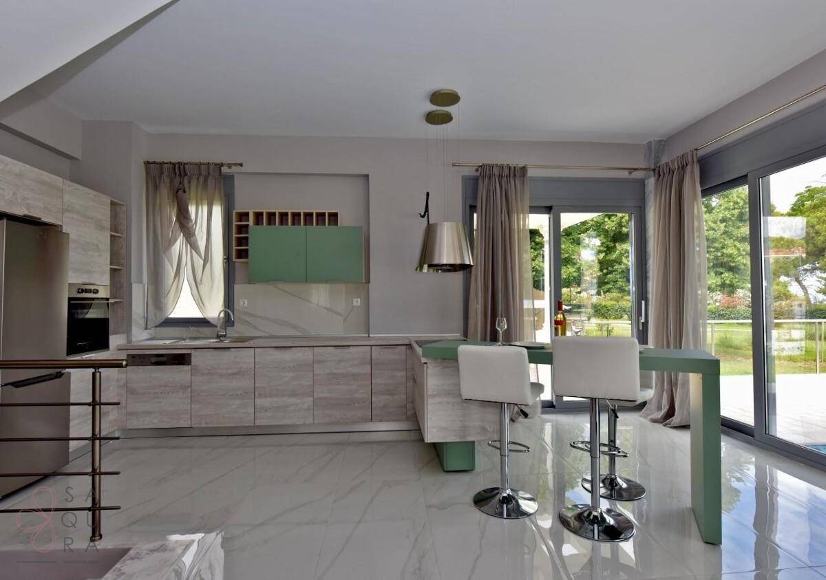 Moderne Küche mit hellen Holzfronten, Kochinsel und Zugang zur Terrasse.