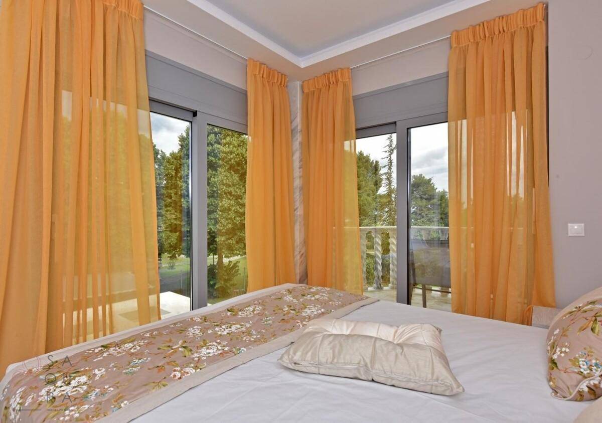 Schlafzimmer mit großen Fenstern, die viel Licht hereinlassen und Zugang zum Balkon bieten.