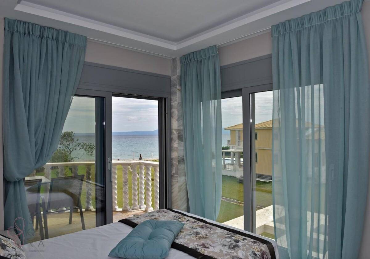 Schlafzimmer mit großen Fenstern und direktem Blick auf das Meer und den Außenbereich.