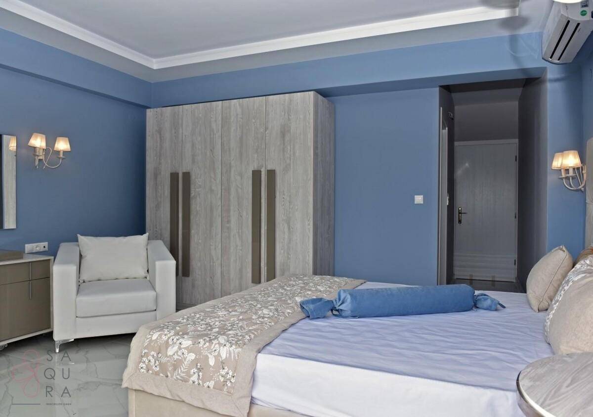 Schlafzimmer mit blauen Wänden, großem Kleiderschrank und bequemen Sitzgelegenheiten.