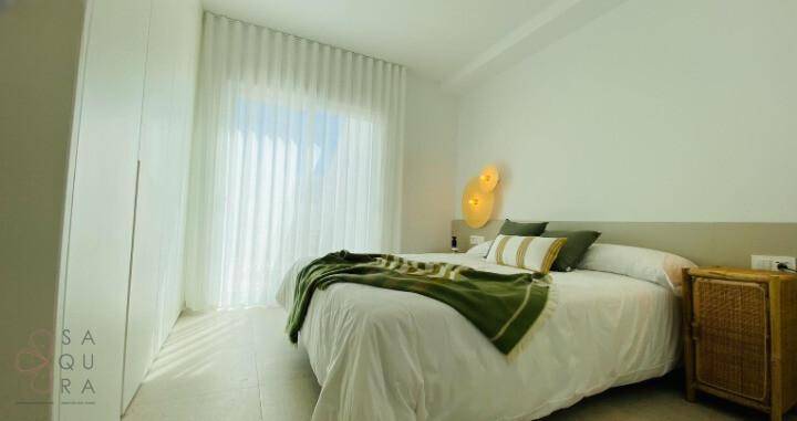 Helles Schlafzimmer mit großem Fenster, Einbauschrank und grünen Akzenten.