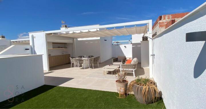 Geräumige Dachterrasse mit moderner Außenküche, Essbereich und Lounge-Möbeln unter einer Pergola.