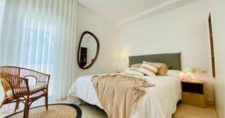 Schlafzimmer mit Doppelbett, modernem Spiegel und hellem Ambiente.