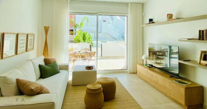 Lichtdurchflutetes Wohnzimmer mit Zugang zur Terrasse, modernem Sofa und TV-Möbeln.