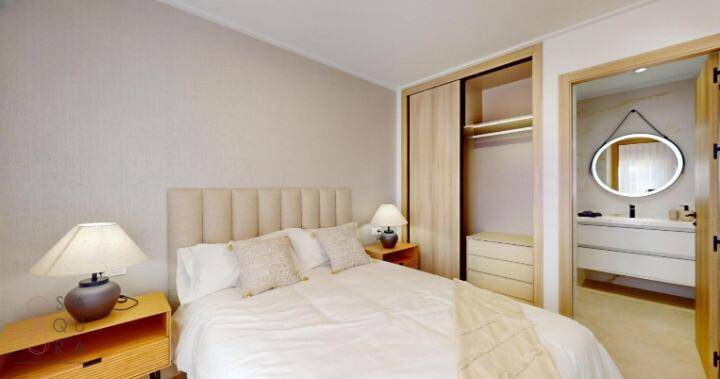 Schlafzimmer mit Doppelbett, Einbauschrank und direktem Zugang zum modernen Badezimmer.
