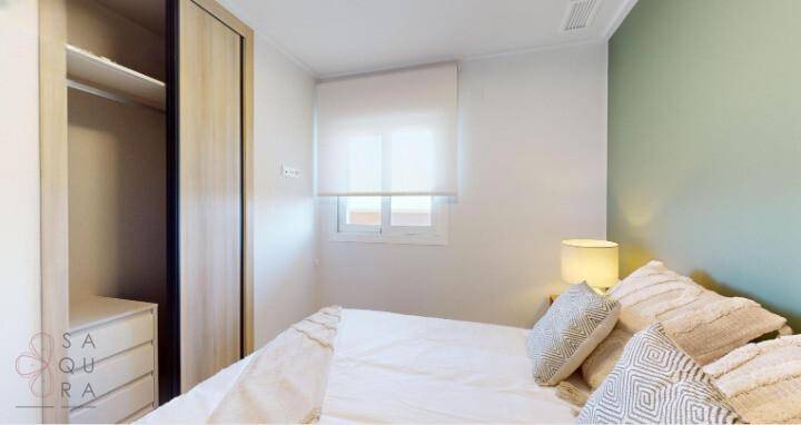 Helles Schlafzimmer mit Einbauschrank und Fenster, das viel Tageslicht hereinlässt.