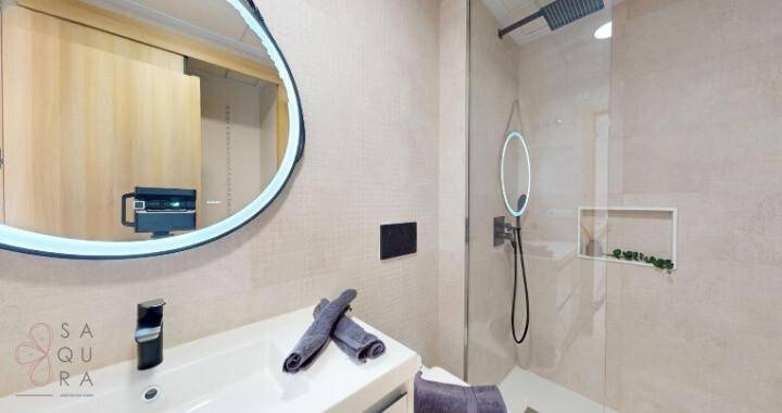 Modernes Badezimmer mit begehbarer Dusche, Einzelwaschbecken und beleuchtetem Spiegel.