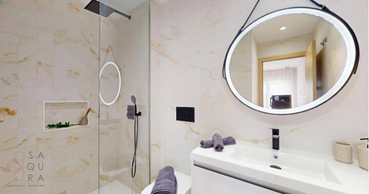 Modernes Badezimmer mit begehbarer Dusche, Einzelwaschbecken und beleuchtetem Spiegel.