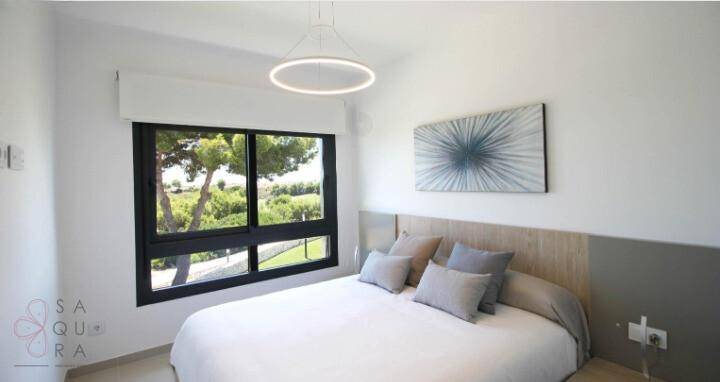 Helles Schlafzimmer mit Doppelbett und großem Fenster mit Baumblick.