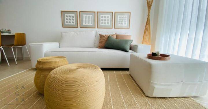 Modern eingerichtetes Wohnzimmer mit bequemer Couch, stilvollen Hockern und heller Dekoration.