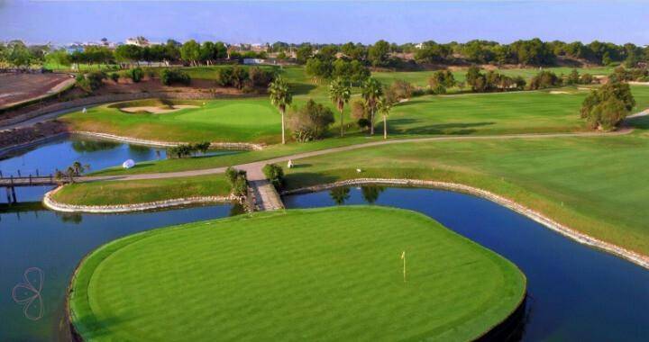 Luftaufnahme eines Golfplatzes mit Inselgrün und Wasserhindernissen.