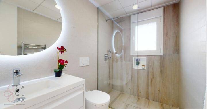 Modernes Badezimmer mit begehbarer Dusche, beleuchtetem Spiegel und Fenster.