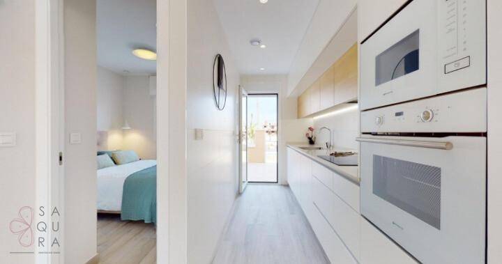 Moderne Einbauküche mit weißen Fronten, integrierten Geräten und Zugang zum Schlafzimmer.