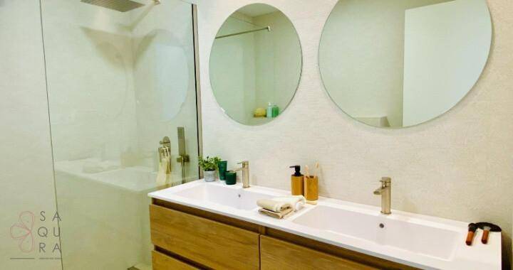 Modernes Badezimmer mit Doppelwaschbecken, runden Spiegeln und begehbarer Dusche.