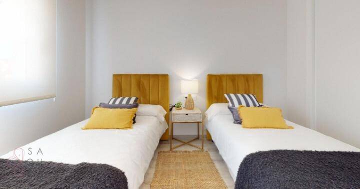 Helles Schlafzimmer mit zwei Einzelbetten, Nachttisch und moderner Dekoration.