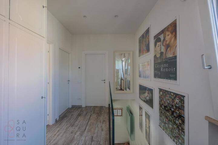 Heller Flur mit Holzfliesenboden und gerahmten Bildern an der Wand, die zur Treppe führen.